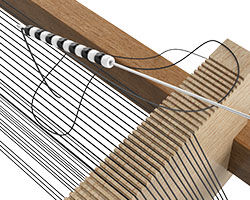 A row of beads on a needle and thread tied to the warp threads of the loom.